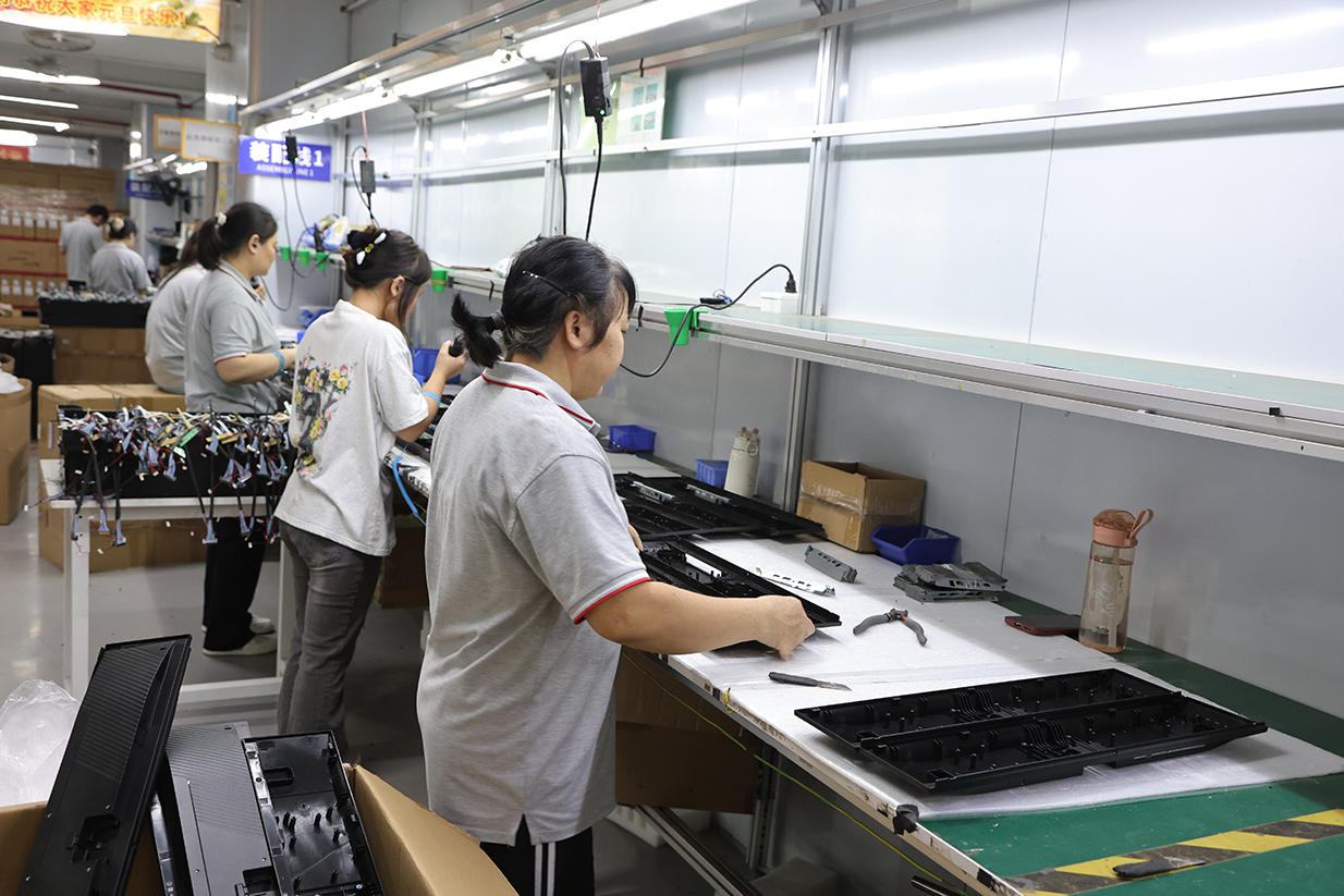 Workers assembling monitor chassis and internal components
